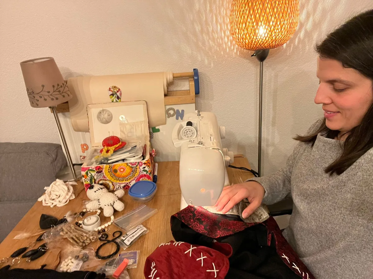 Es kann Wochen dauern, bis ein Kostüm fertig genäht ist. Eine Frau sitzt an der Nähmaschine und näht ein Kostüm.